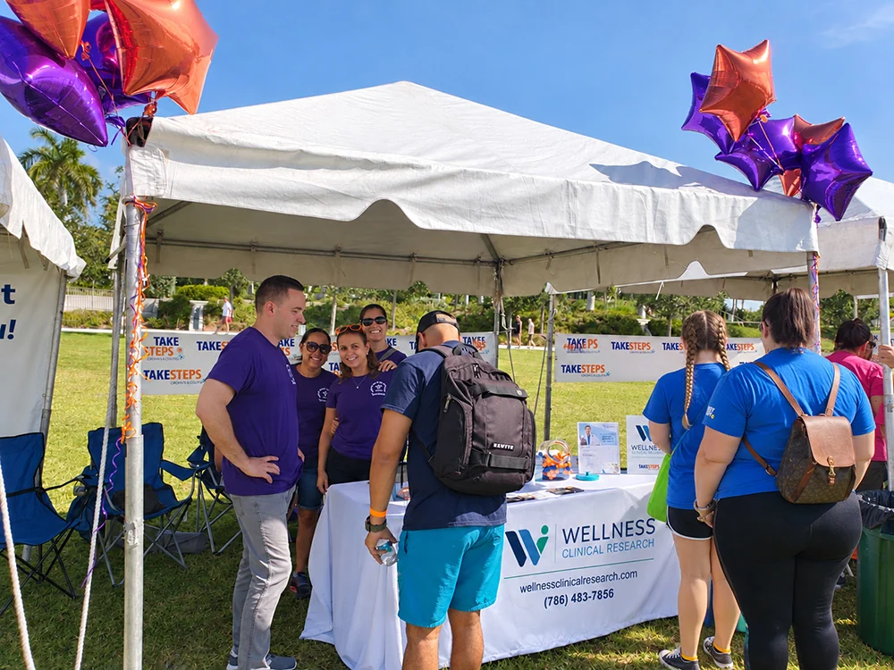 Wellness Clinical Research team speaking with visitors at a Take Steps community event